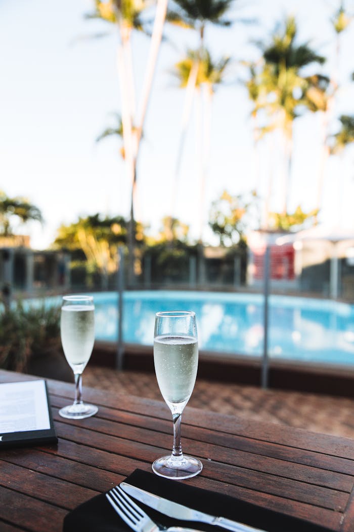 Two glasses of white wine on a dining table by the poolside